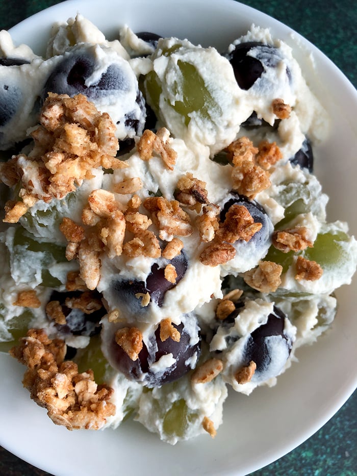 Creamy Grape Salad topped with granola on a white plate. 