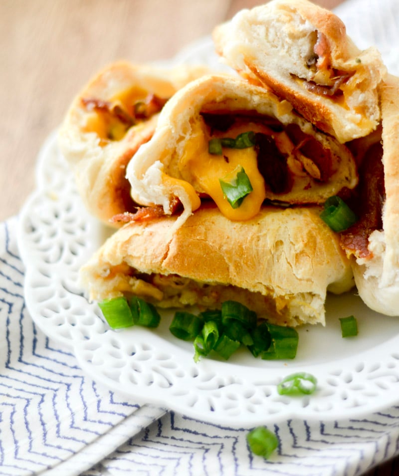Cheddar Bacon Bombs garnished with green onions on a white plate.