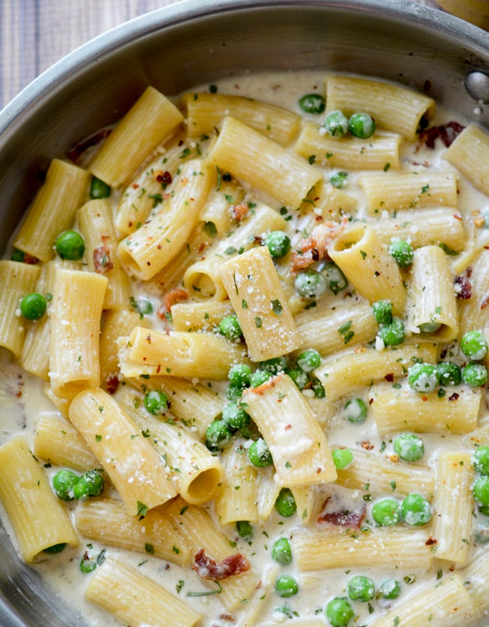 Alfredo with bacon and peas cooked in a pan. 