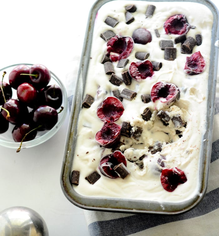 Chocolate cherry chunk ice cream in a mini loaf pan next to cherries.