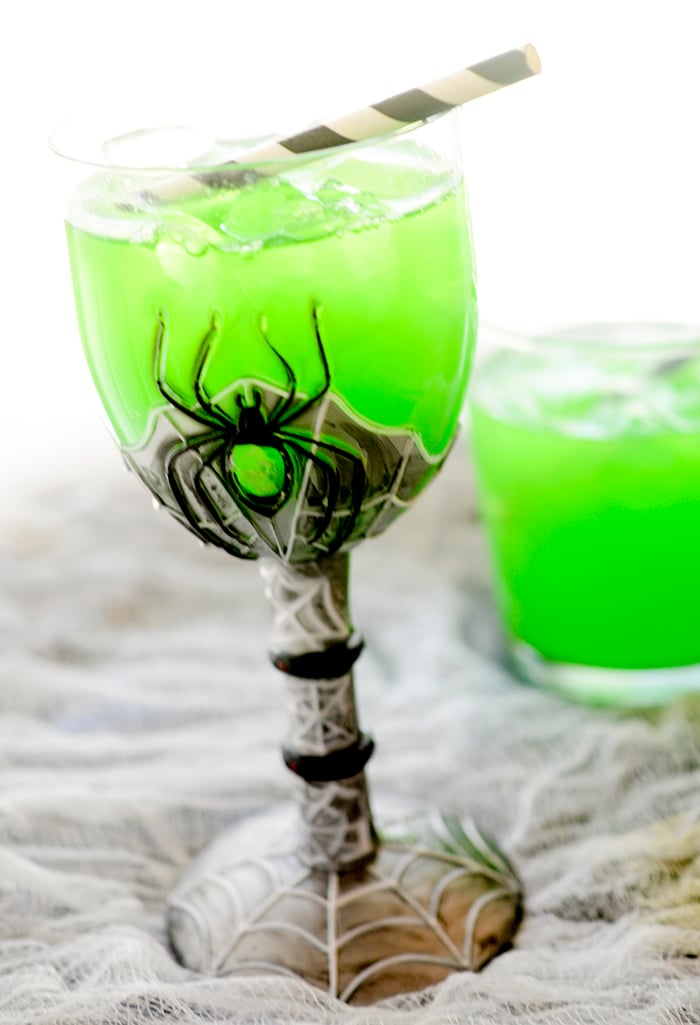 Witch's Brew Cocktail in a spooky spider glass with a straw. 
