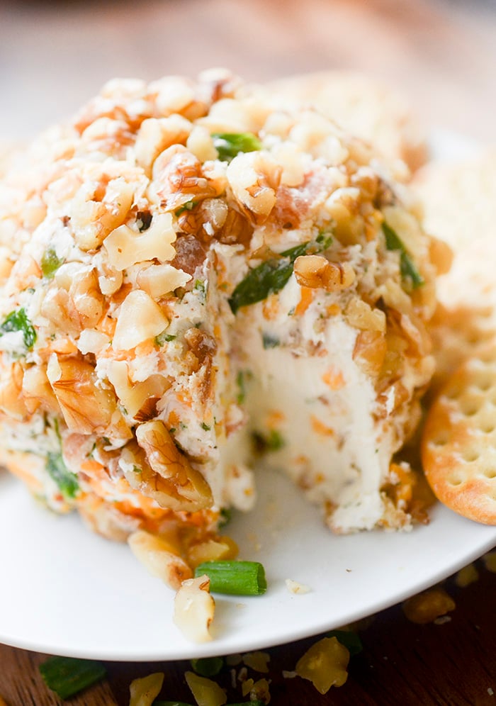 Cheddar Bacon Ranch Cheese Ball on a white plate served with some butter crackers. 