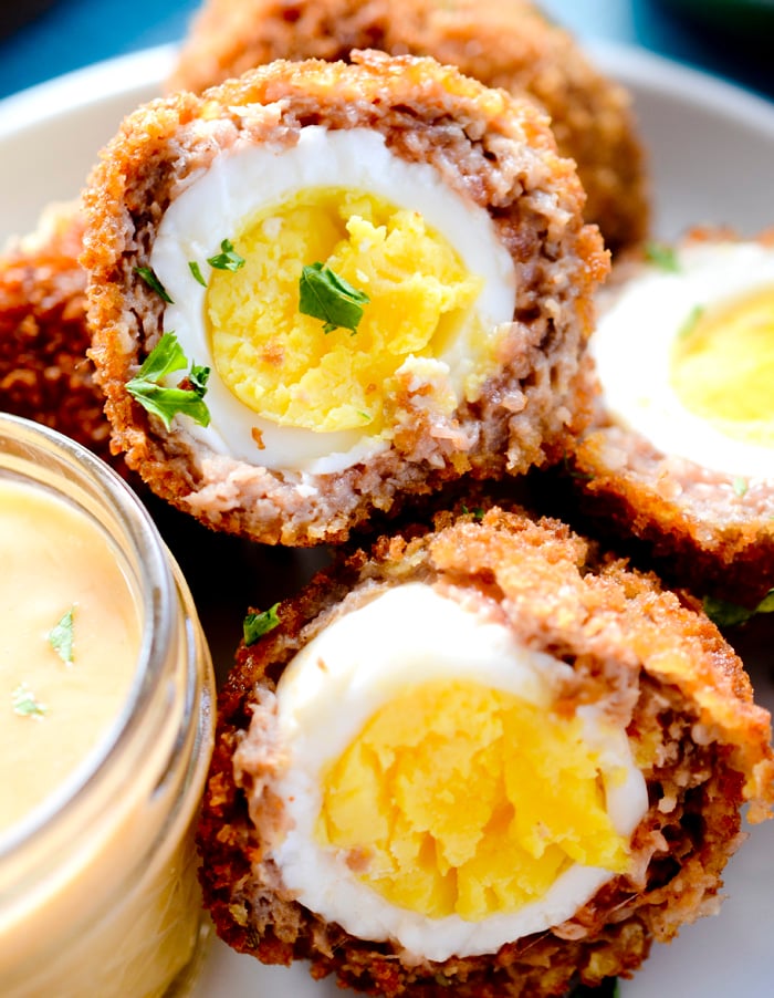 Homemade air fryer scotch eggs next to sauce. 