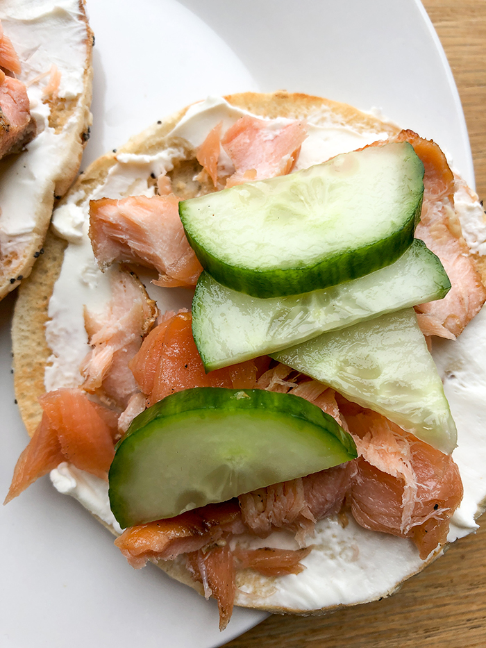 Smoked Salmon spread on a bagel and topped with cucumbers. 