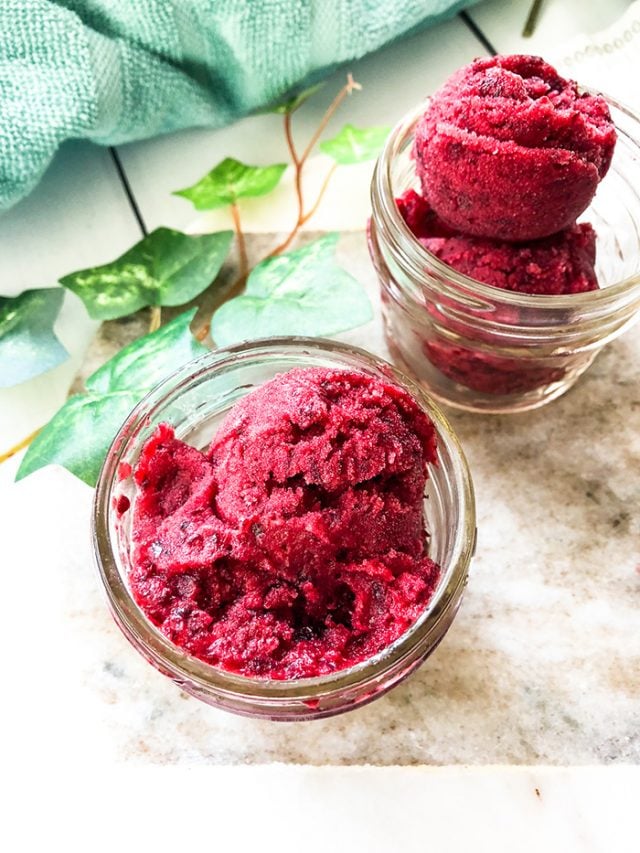 Cherry sorbet in glass jars next to a blue napkin. 