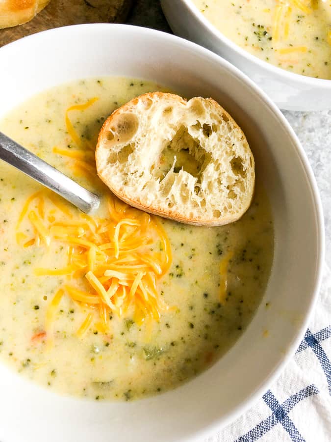 Broccoli cheddar soup topped with cheese in a white bowl. 