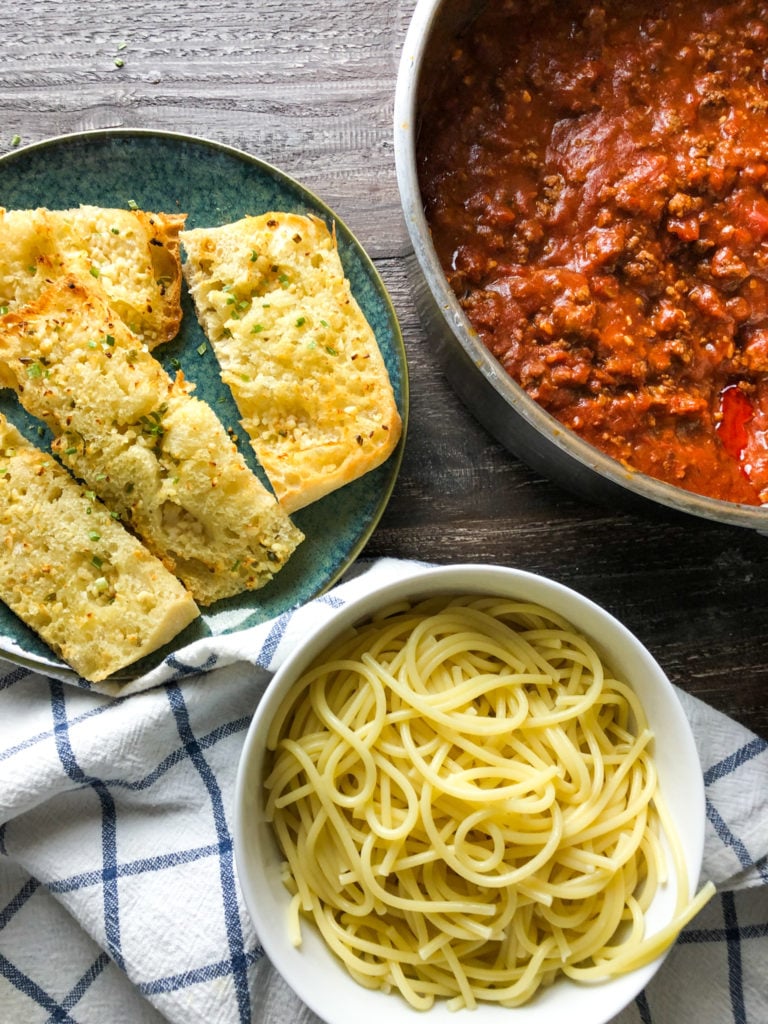 Ai fried garlic bread next to spaghetti and meat sauce with noodles. 