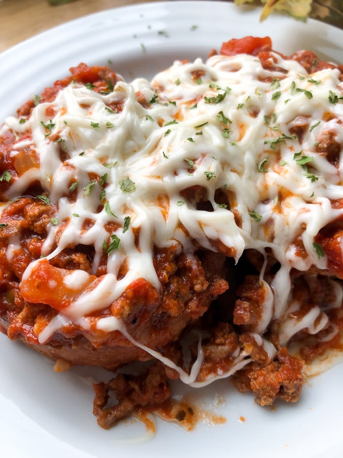 spaghetti sauce over texas toast garlic bread topped with cheese and on a white plate 