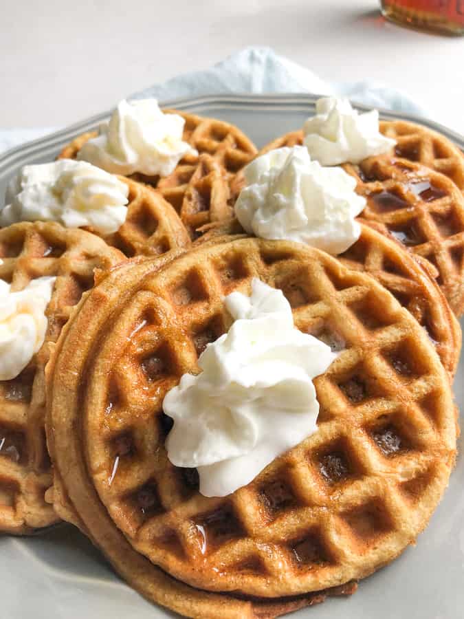 Pumpkin Spice Waffles topped with syrup and whipped cream.