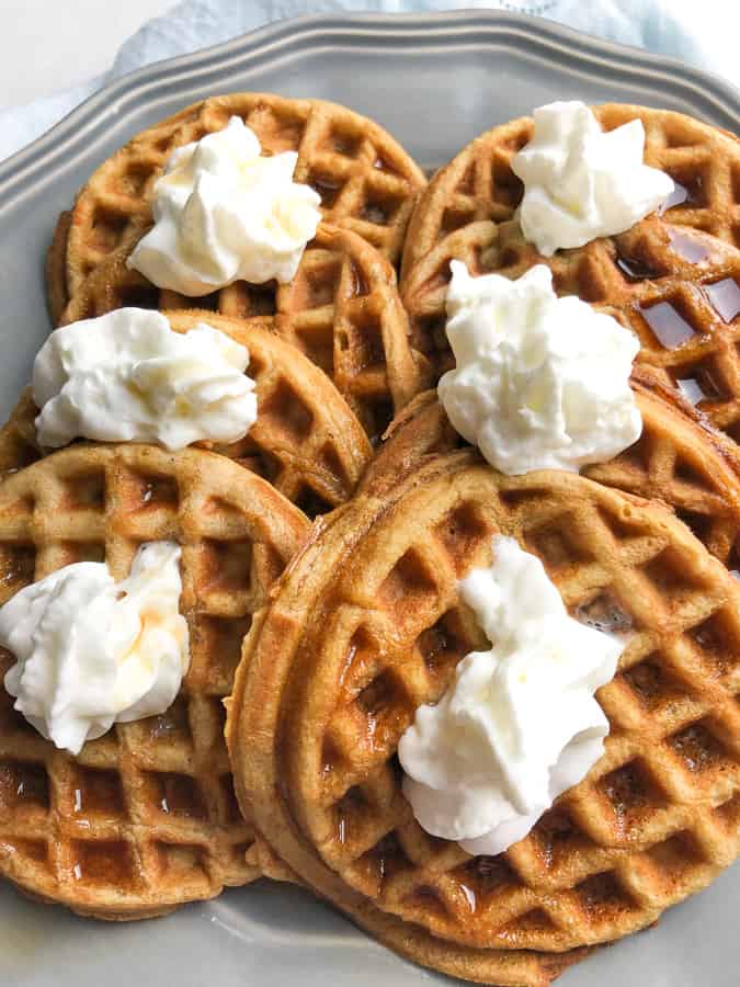 Pumpkin Spice Waffles topped with syrup and whipped cream. 