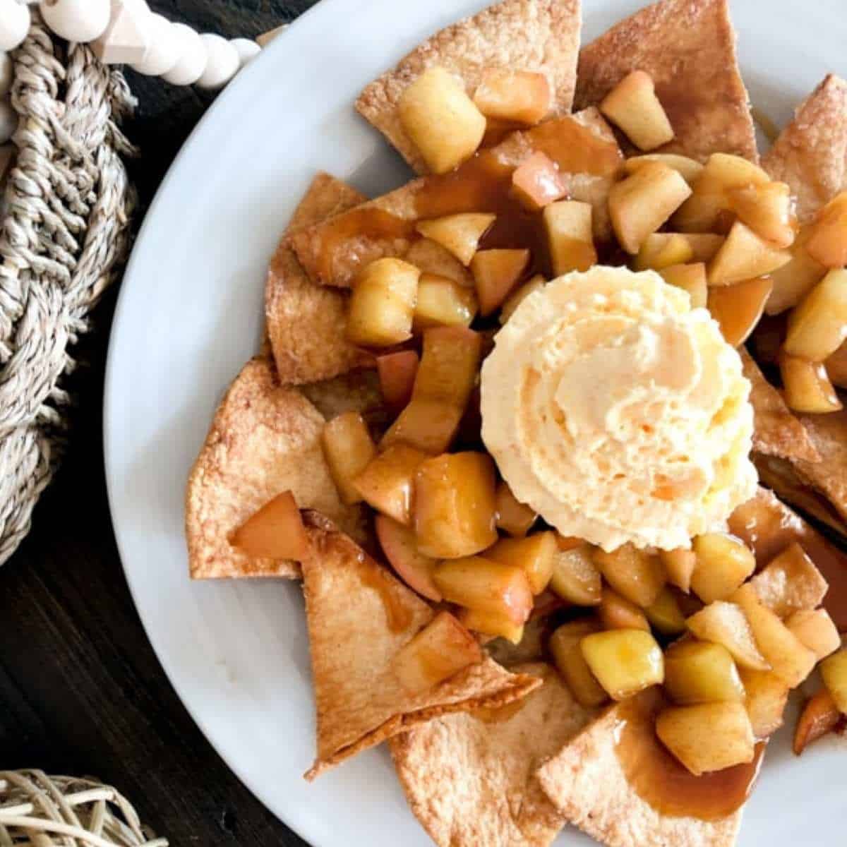 Apple Pie Nachos on a white plate topped with whipped topping.
