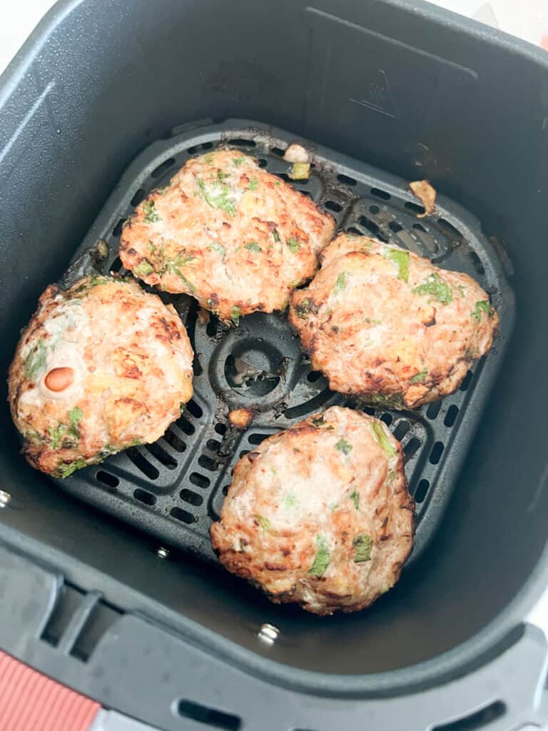 Finished air fried turkey burgers in air fryer basket.