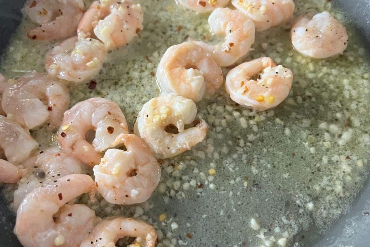 Shrimp cooking in a skillet with garlic and butter. 
