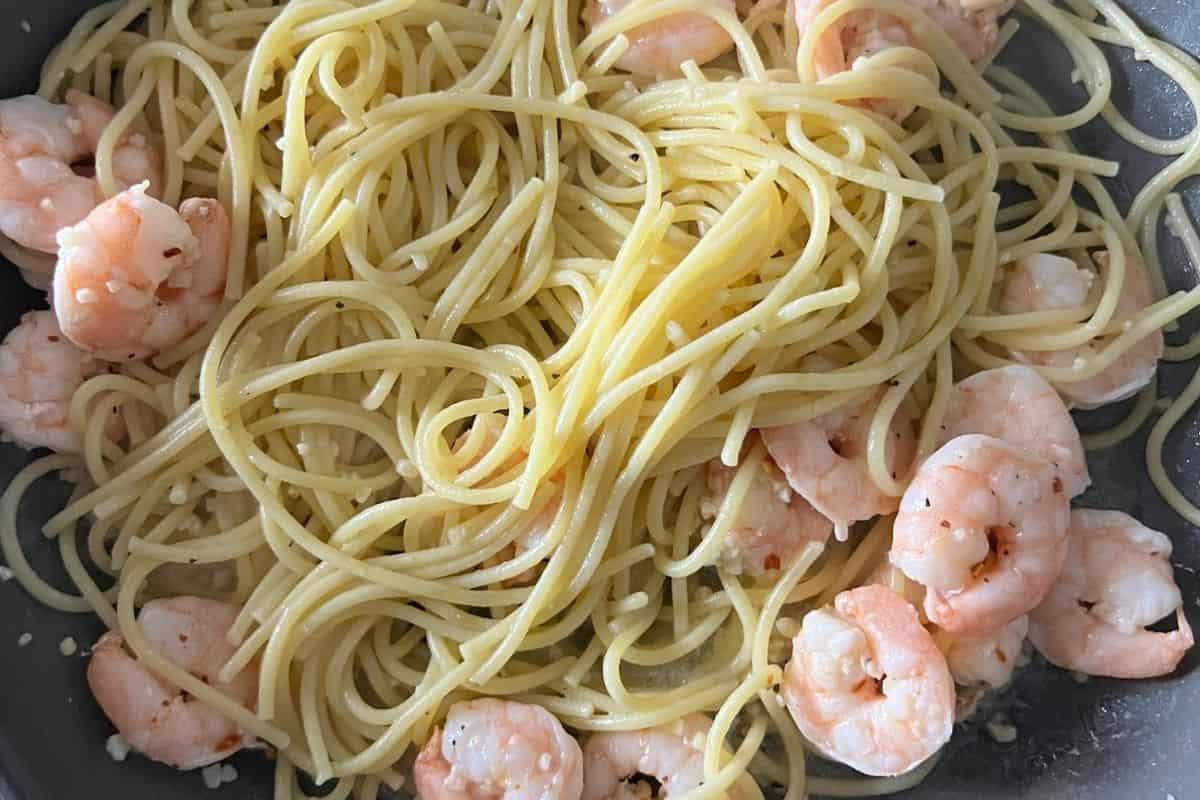 Noodles combined with shrimp and garlic sauce in a pan. 