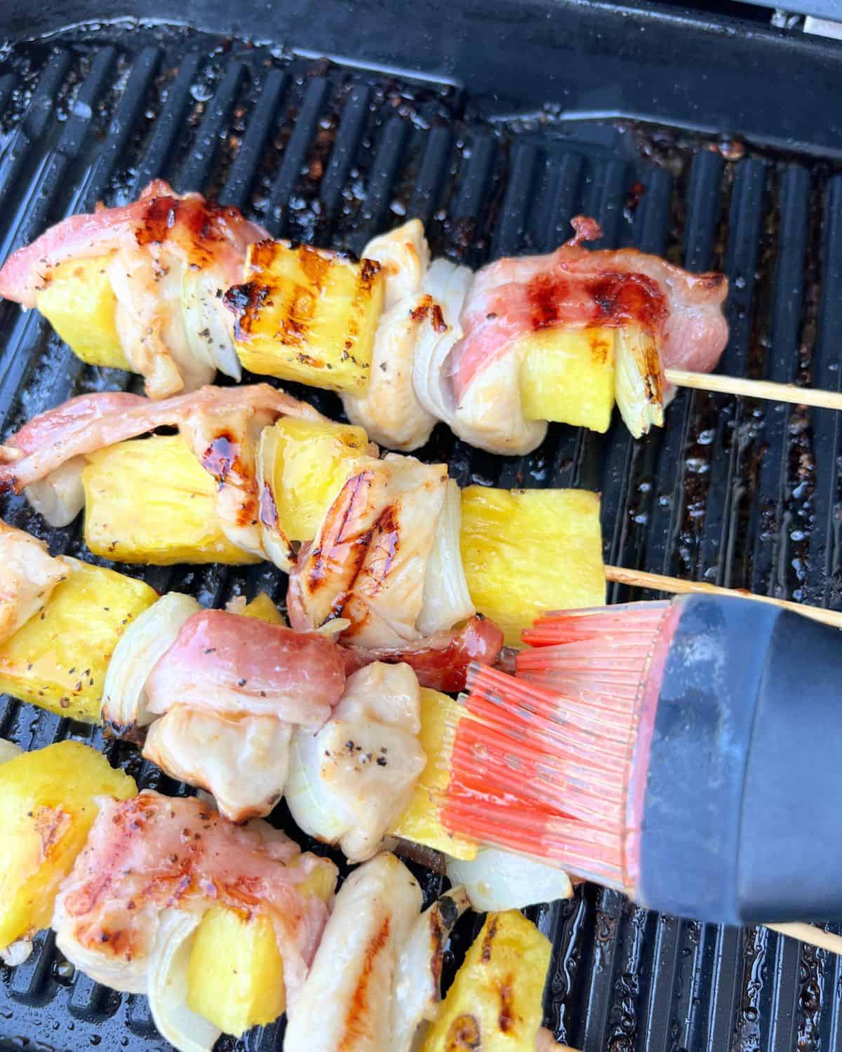 Pineapple glaze being brushed on to the skewers. 