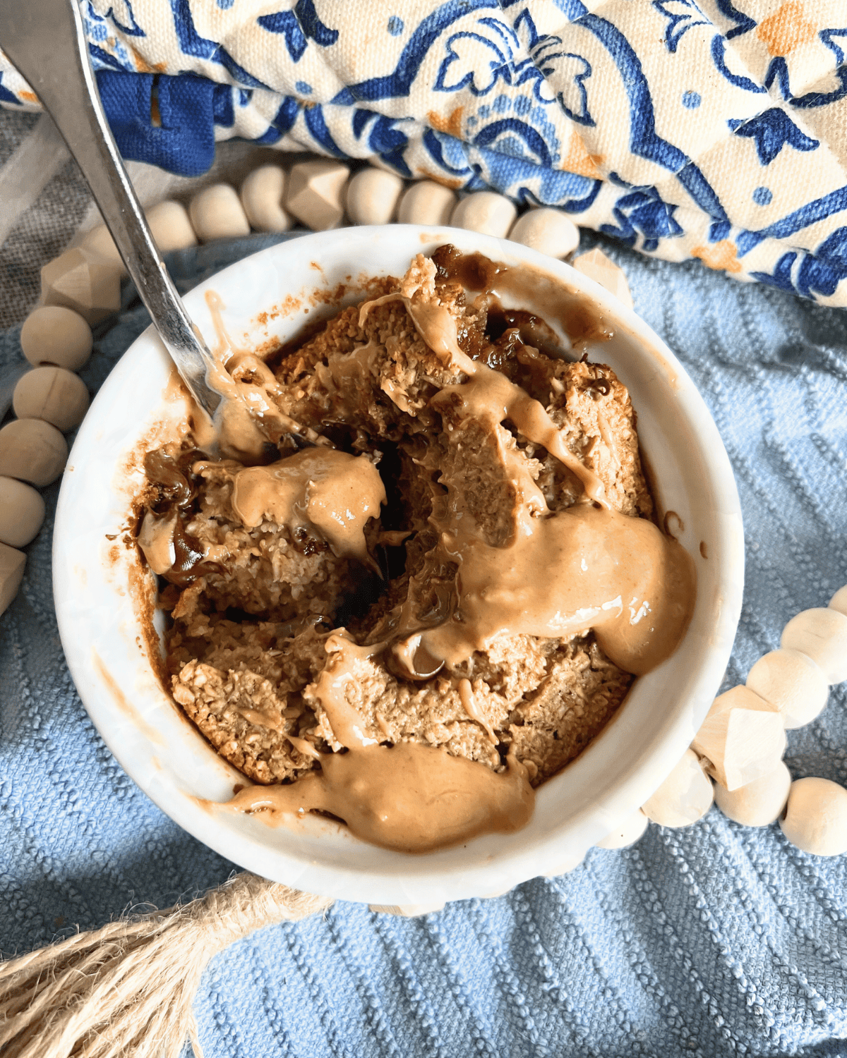 Baked oats drizzled with peanut butter in a white ramekin. 