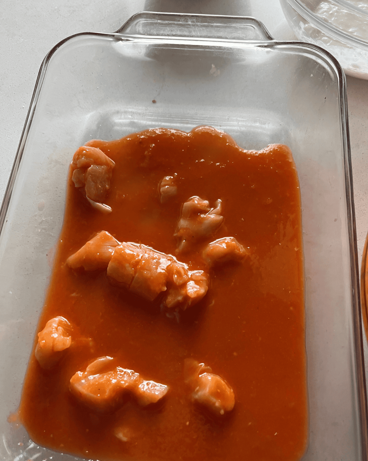 a cup of chicken and sauce in an oven proof baking dish 