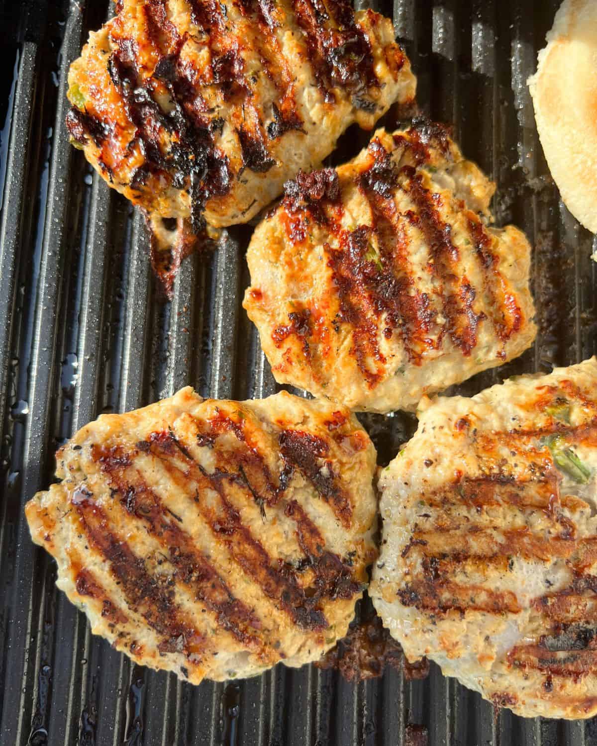 Cooked chicken burgers on top of a grill. 