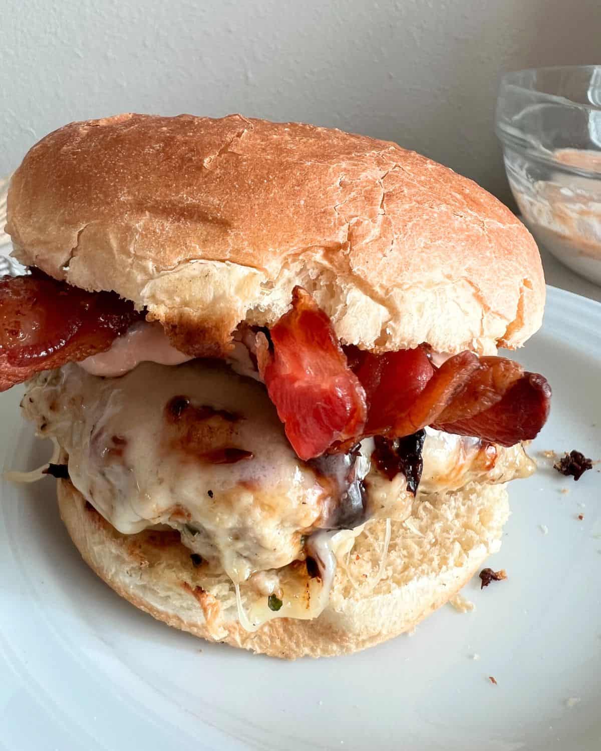 Assembled grilled chicken burger with sauce and bacon. 