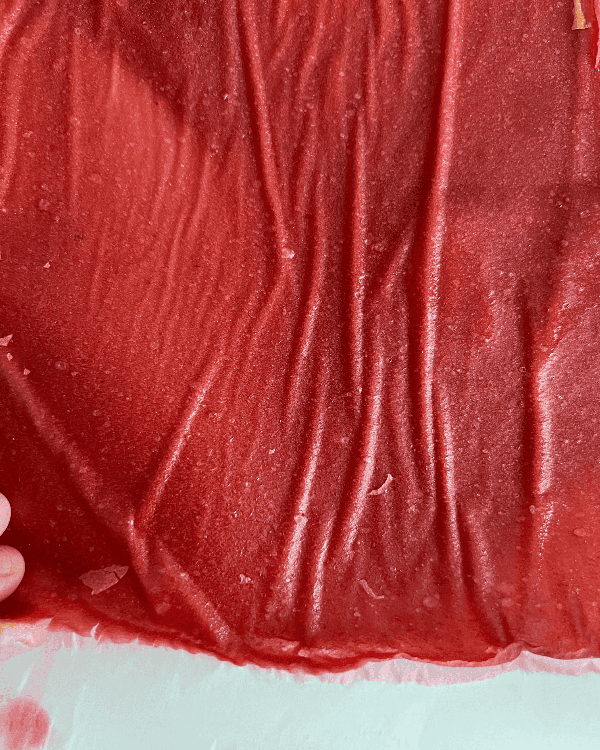 Finished fruit rolls being peeled off parchment paper.