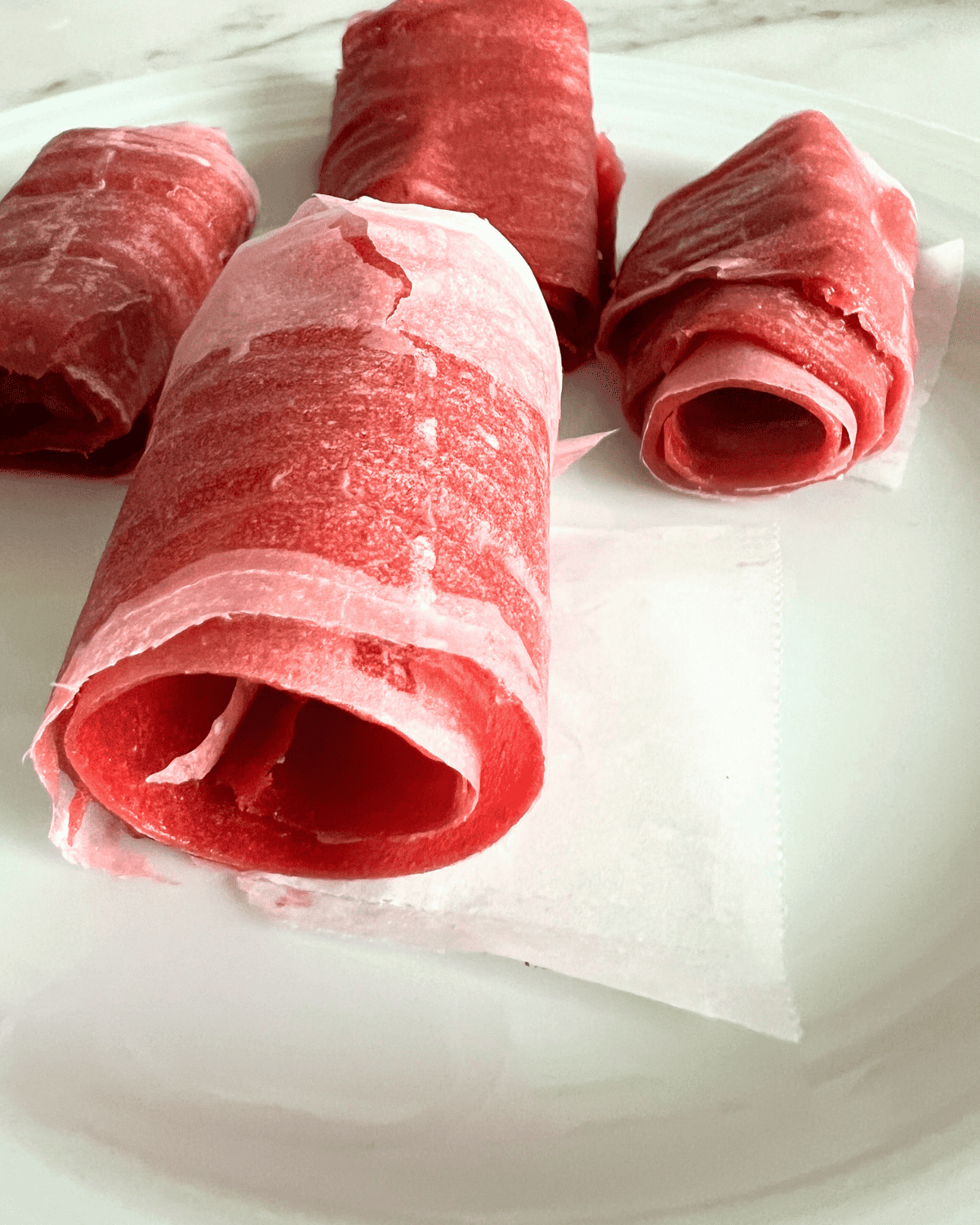 Finished fruit leather rolled up in parchment paper.
