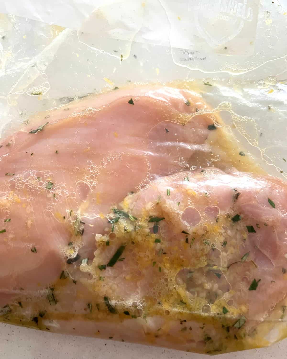 Chicken breasts marinaded in lemon marinade in a zip lock bag. 