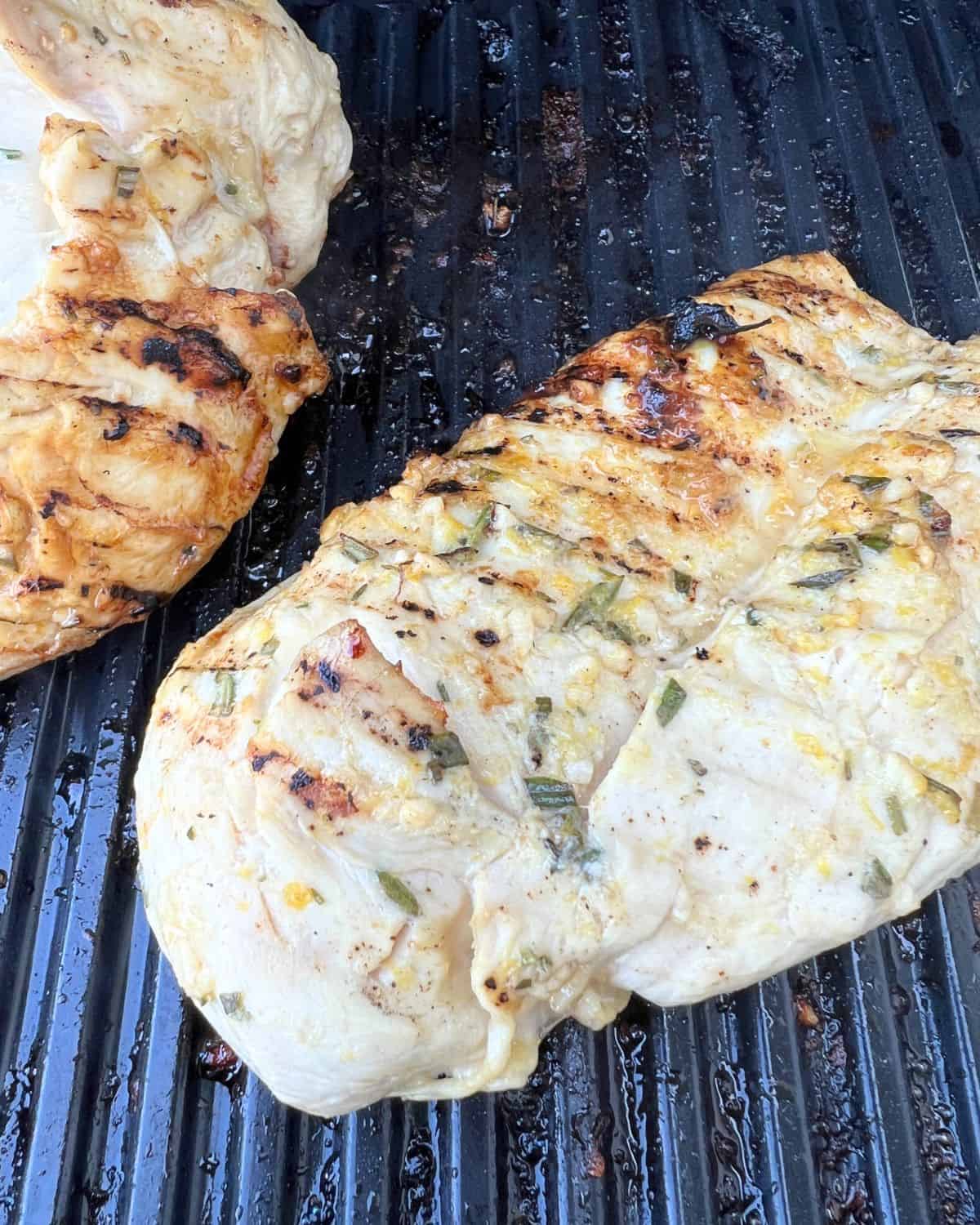 Grilled flavorful lemon chicken cooking on a grill. 