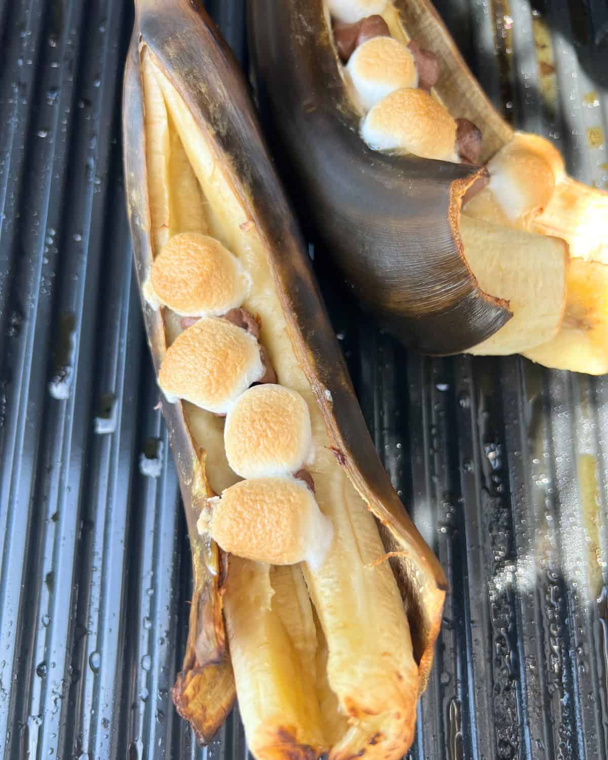 Finished grilled bananas with marshmallows and chocolate chips on a grill. 