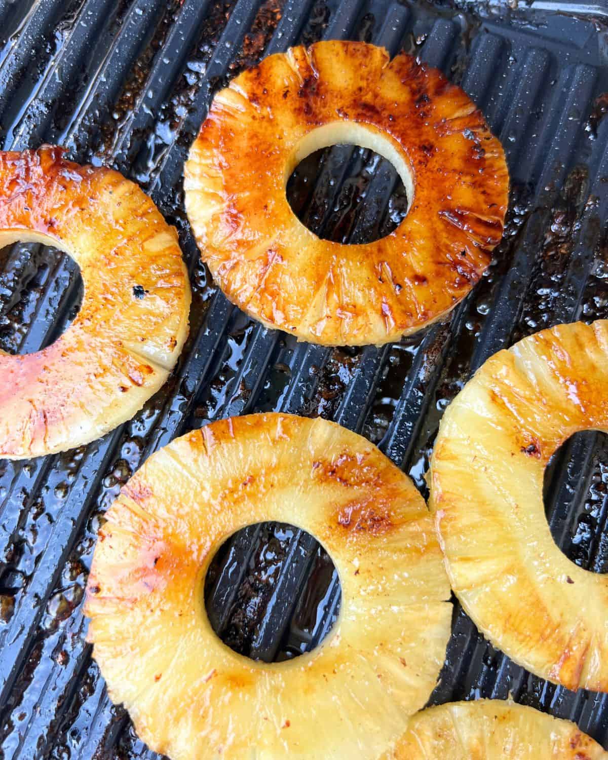 Marinaded pineapple cooking on a grill. 