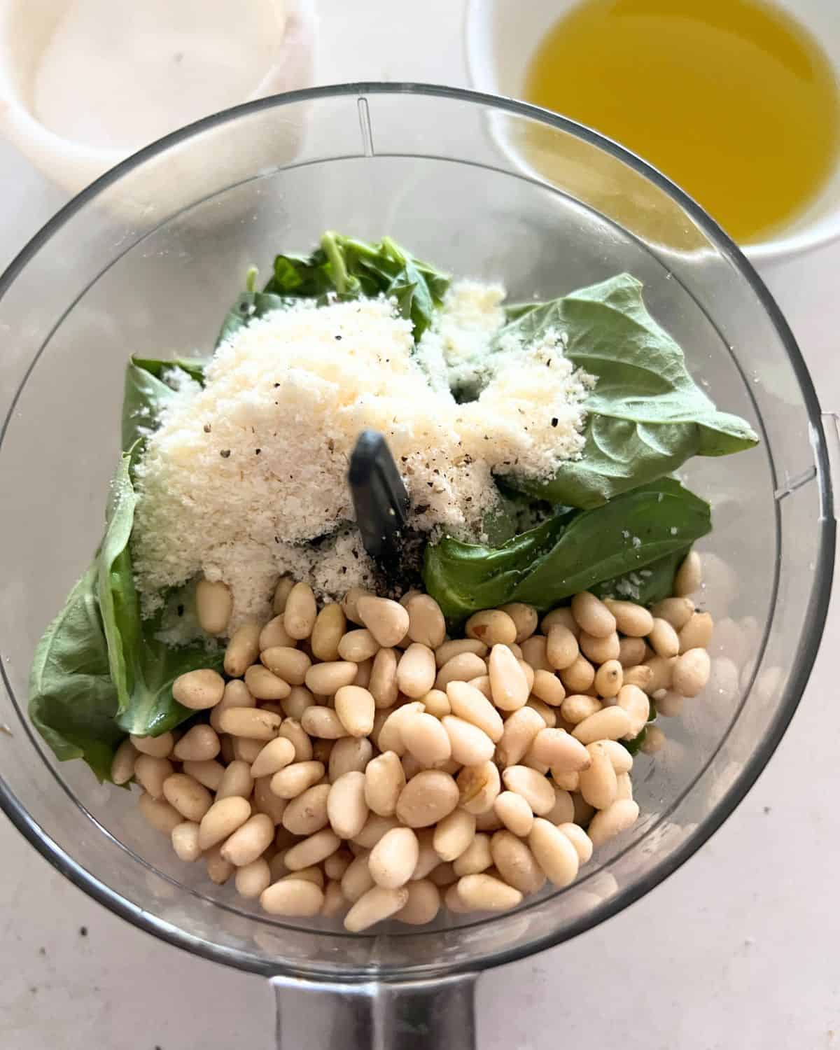 Basil, cheese, pine nuts, and olive oil ready to blended in a food processor.