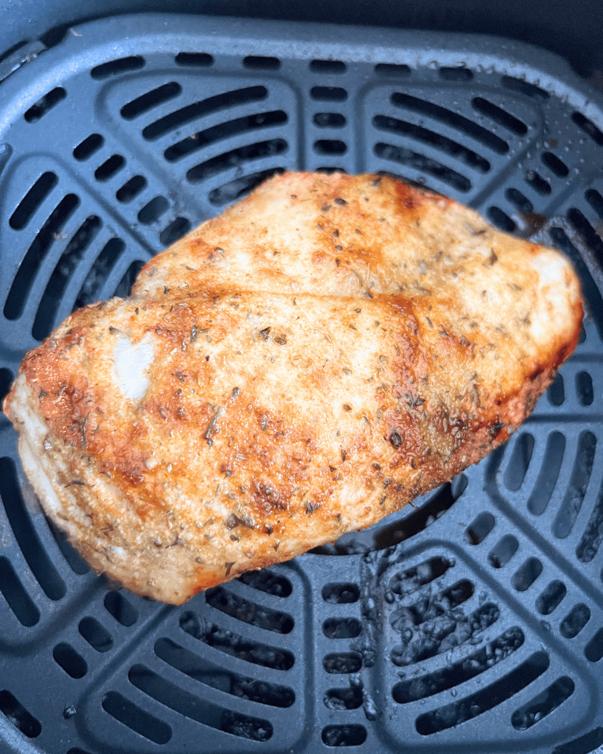 finished seasoned chicken breast in air fryer basket 