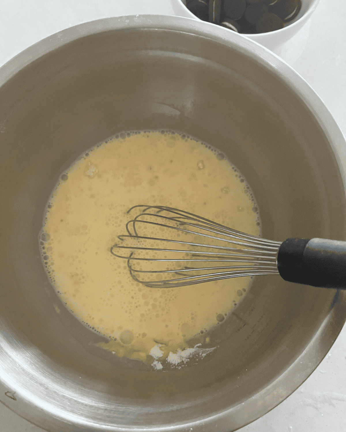 instant pudding mix and milk being whisked together in a bowl 