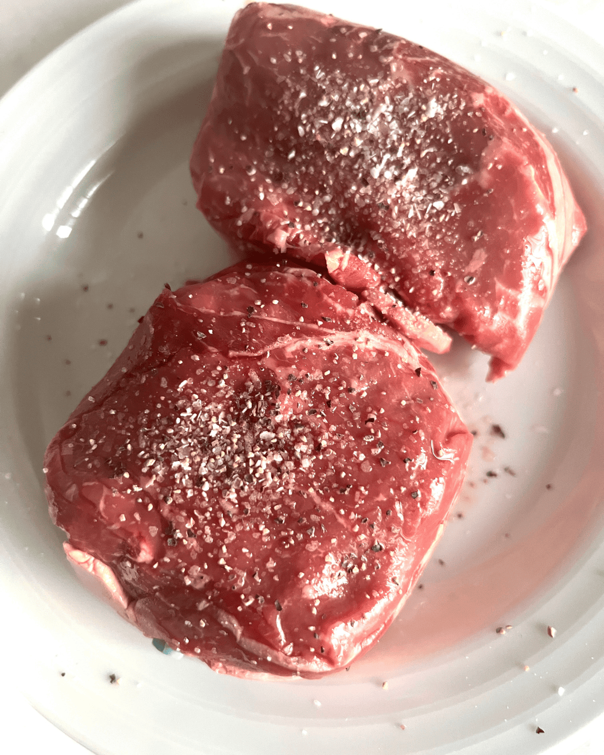 Seasoned petite top sirloin steaks with salt and pepper. 