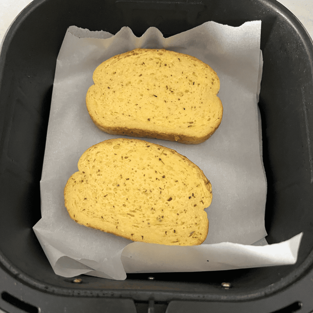 placing garlic bread in an air fryer basket 
