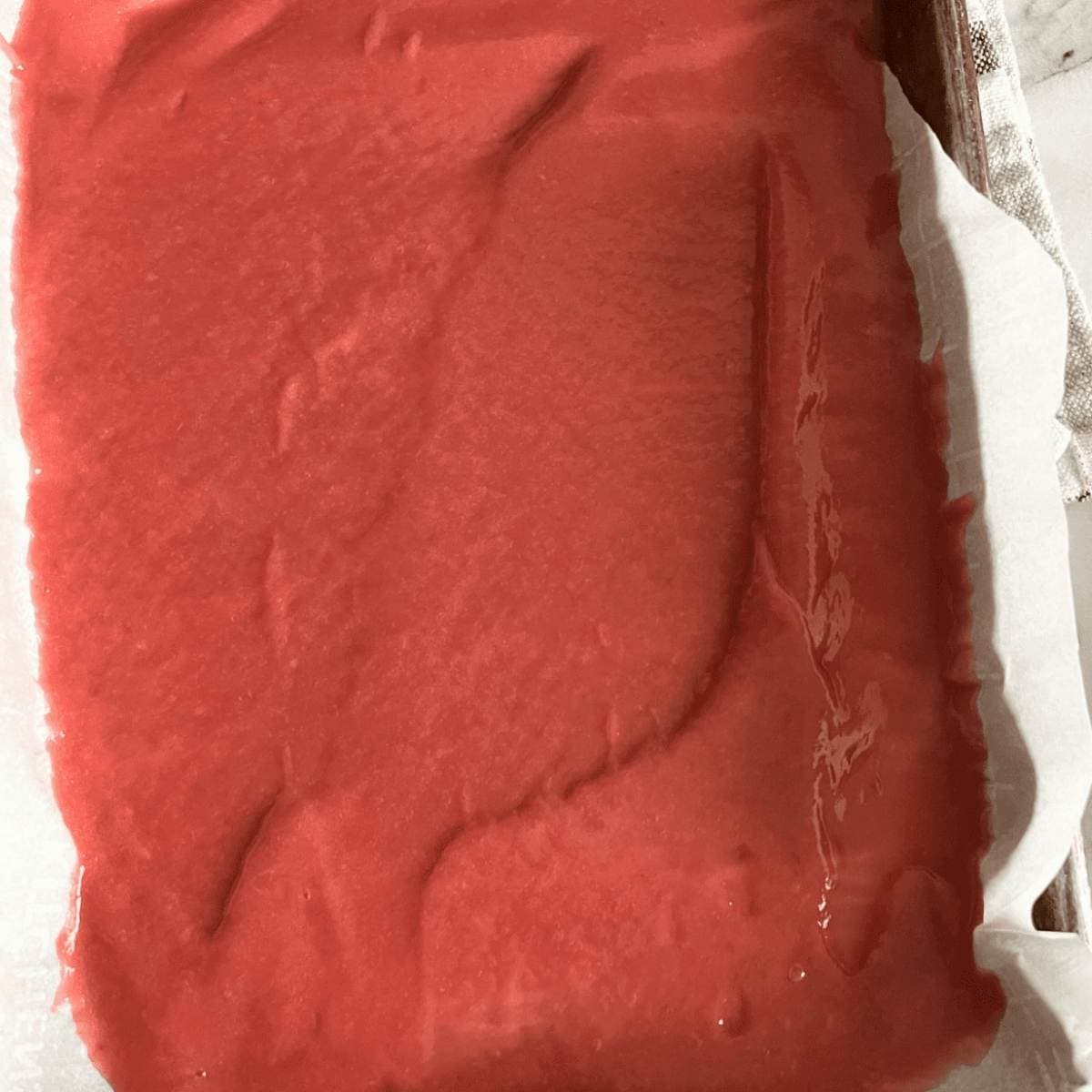 Pureed rhubarb leather spread out on baking sheet.