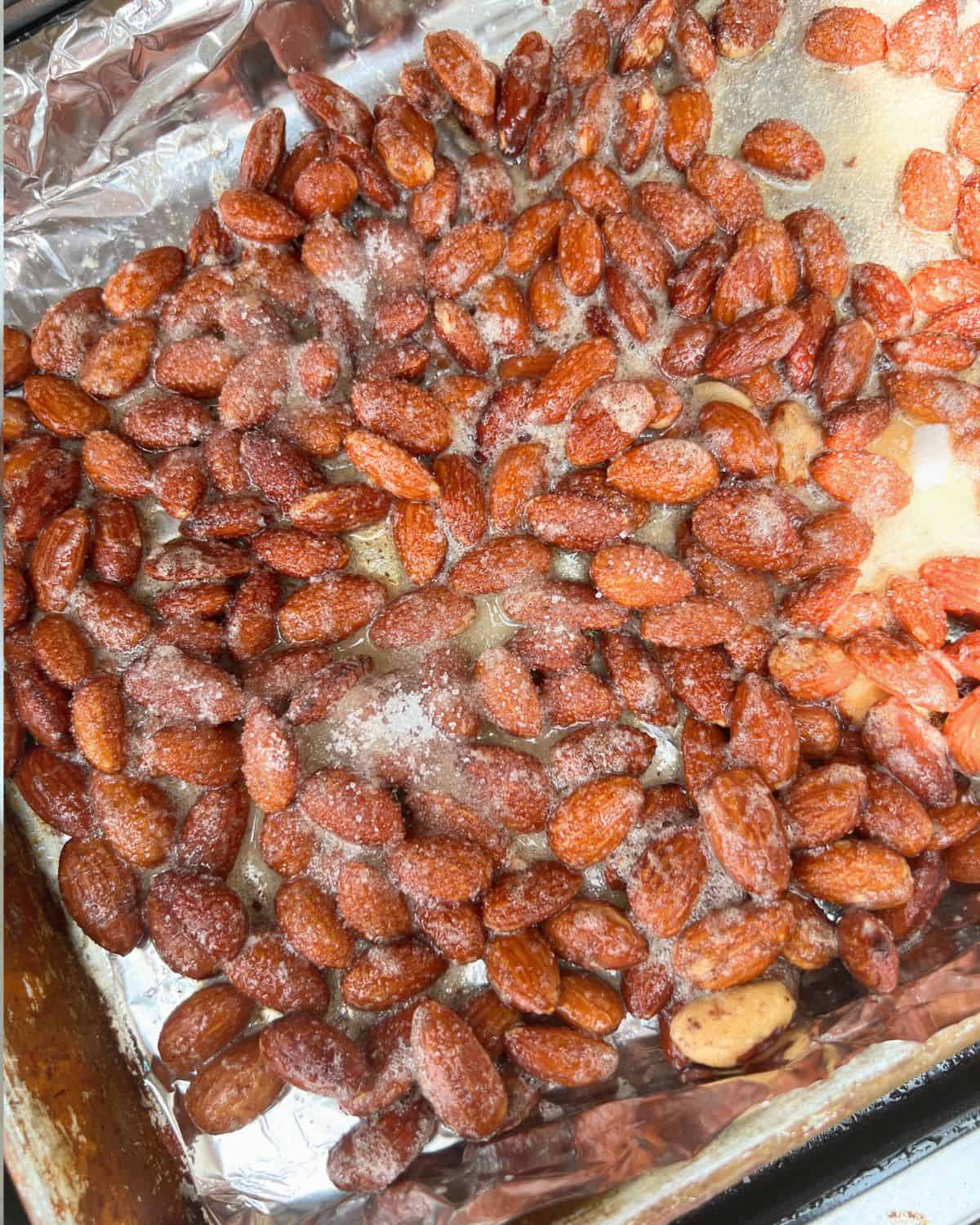 Seasoned smoked almonds on a lined baking sheet with foil. 