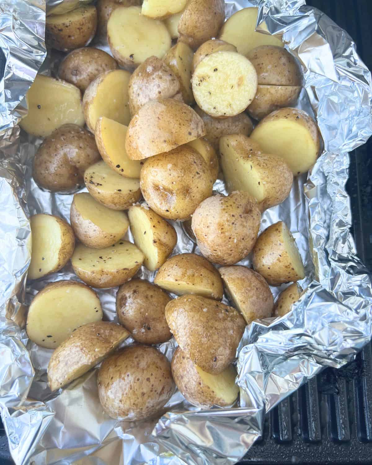 Seasoned yellow potatoes with salt, olive oil, and pepper wrapped in foil. 