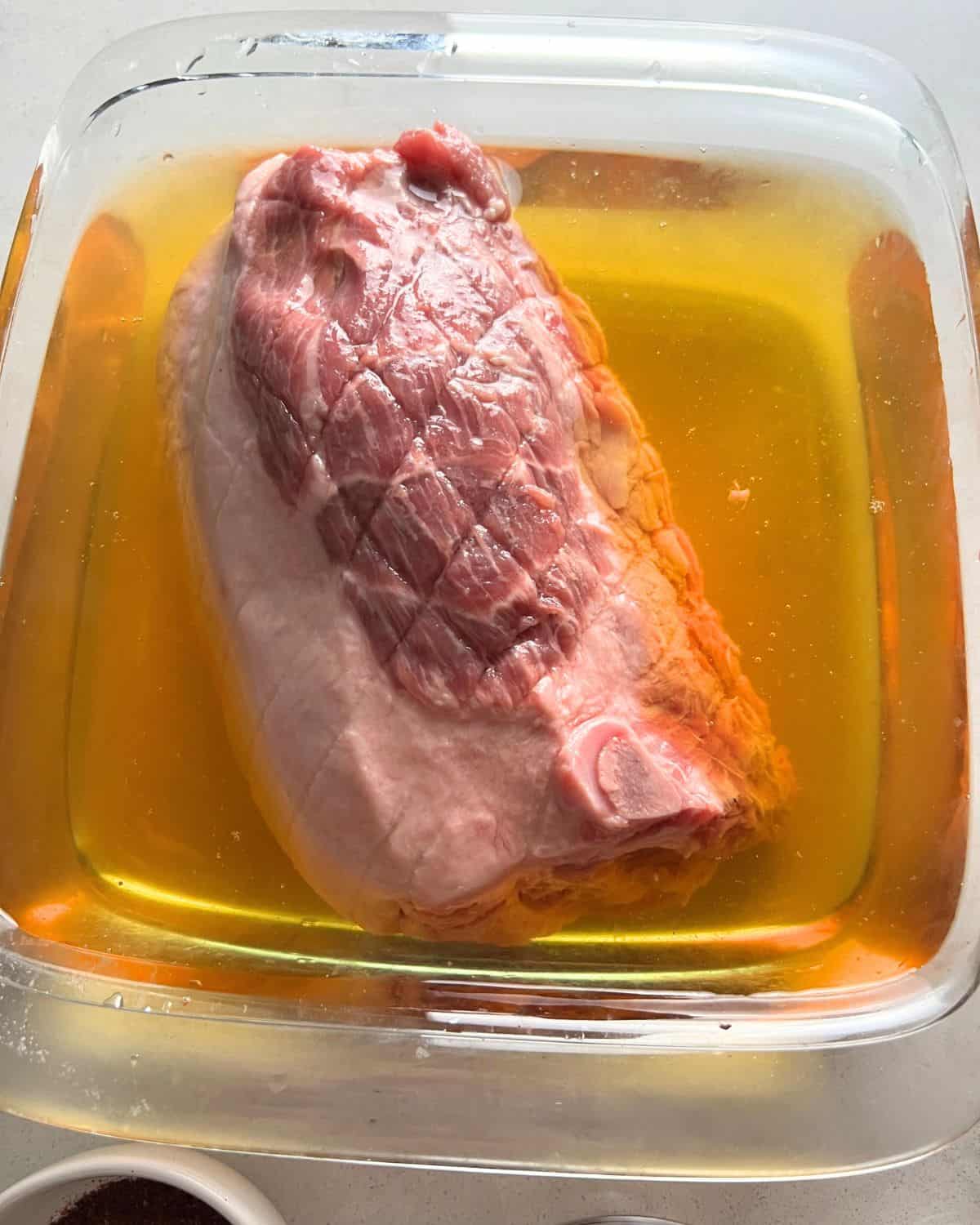 Pork shoulder roast brining in a bowl. 