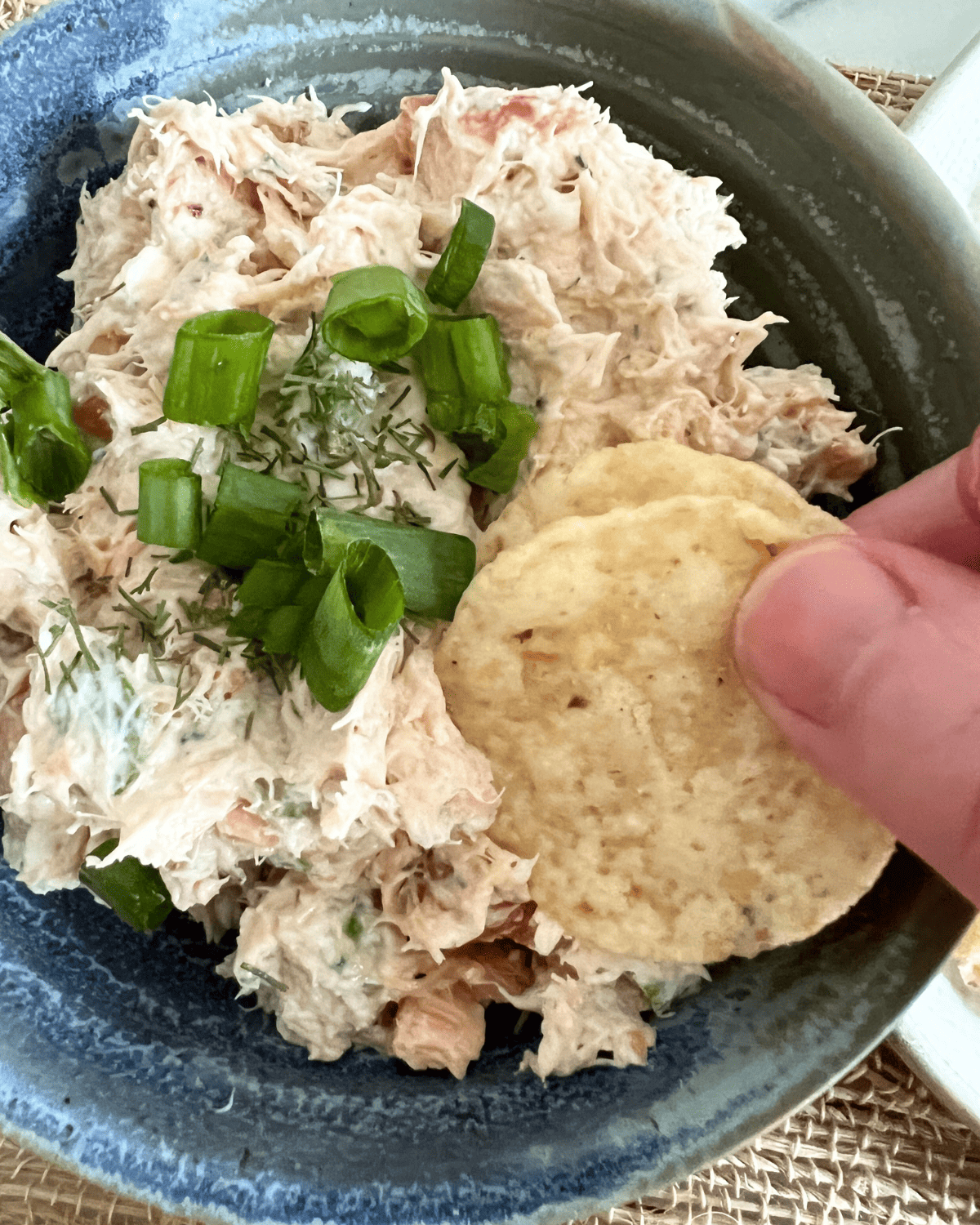 Smoked salmon dip in a blue bowl tooped with green onions. 