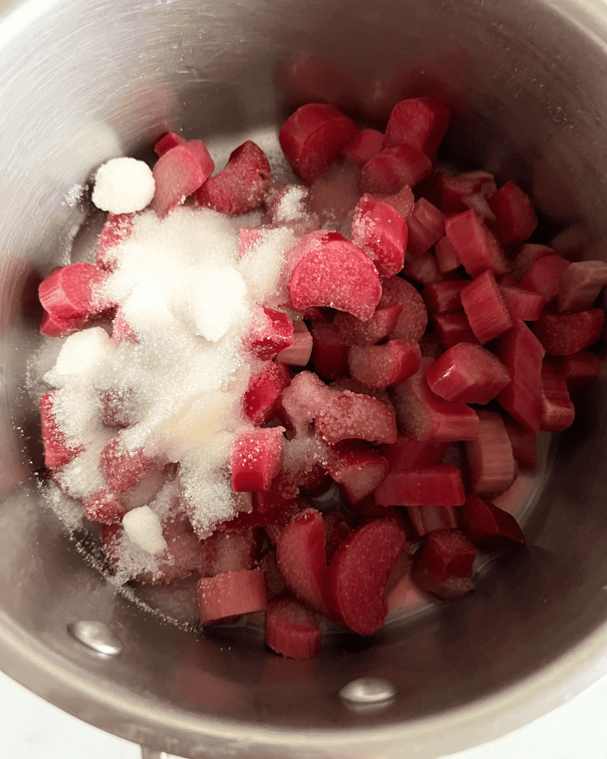 Rhubarb, sugar, and lemon juice in a sauce pan cooking on the stove 