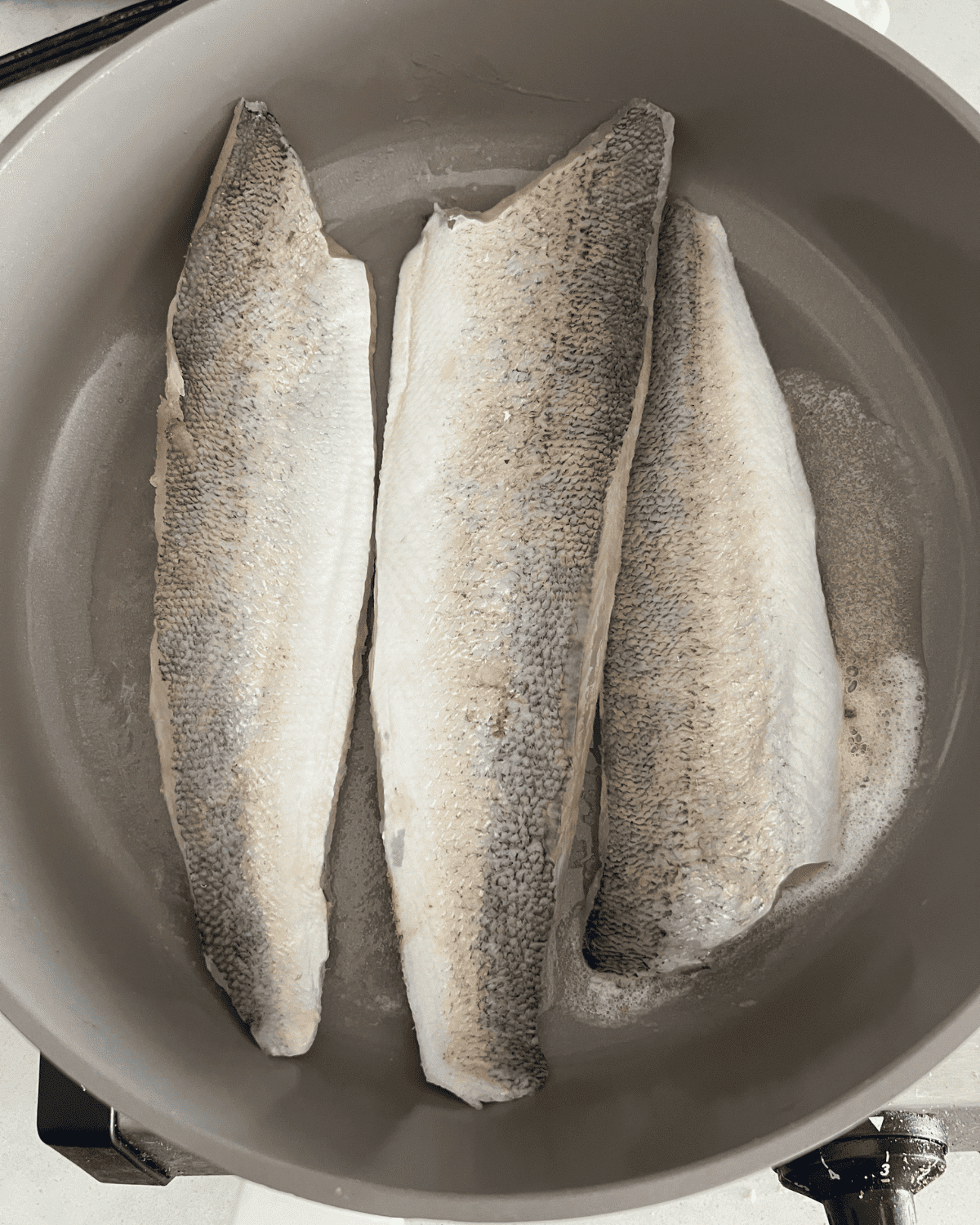 walleye cooking over butter in a skillet 