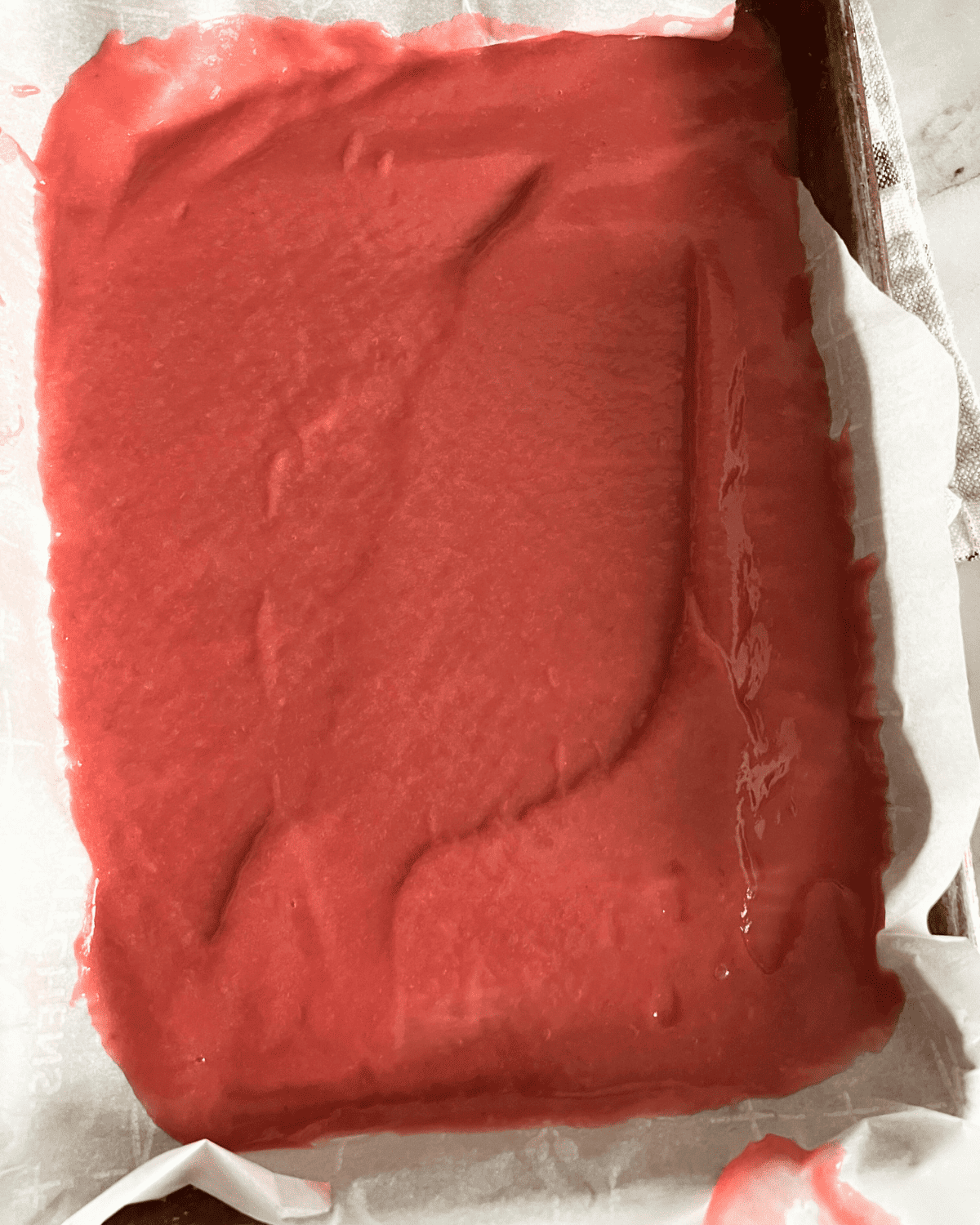 Pureed Rhubarb spread out on a parchment lined baking sheet. 