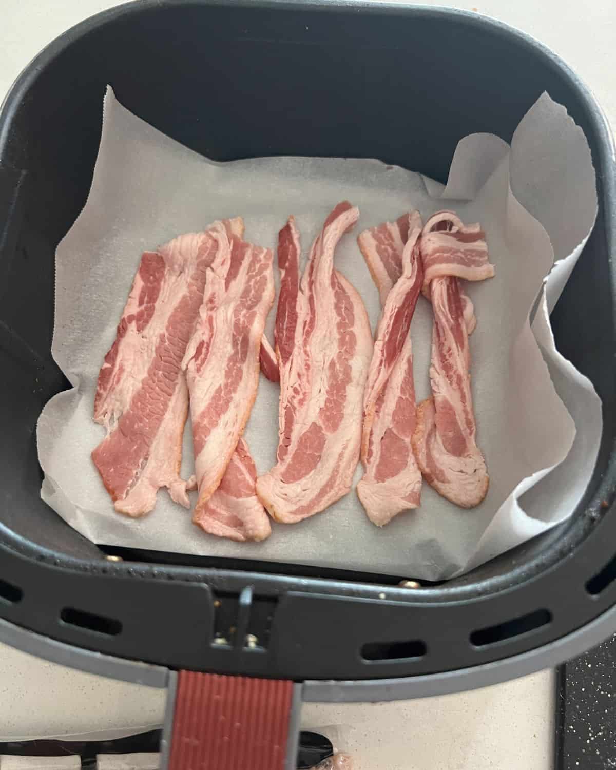 Bacon in air fryer over parchment paper.