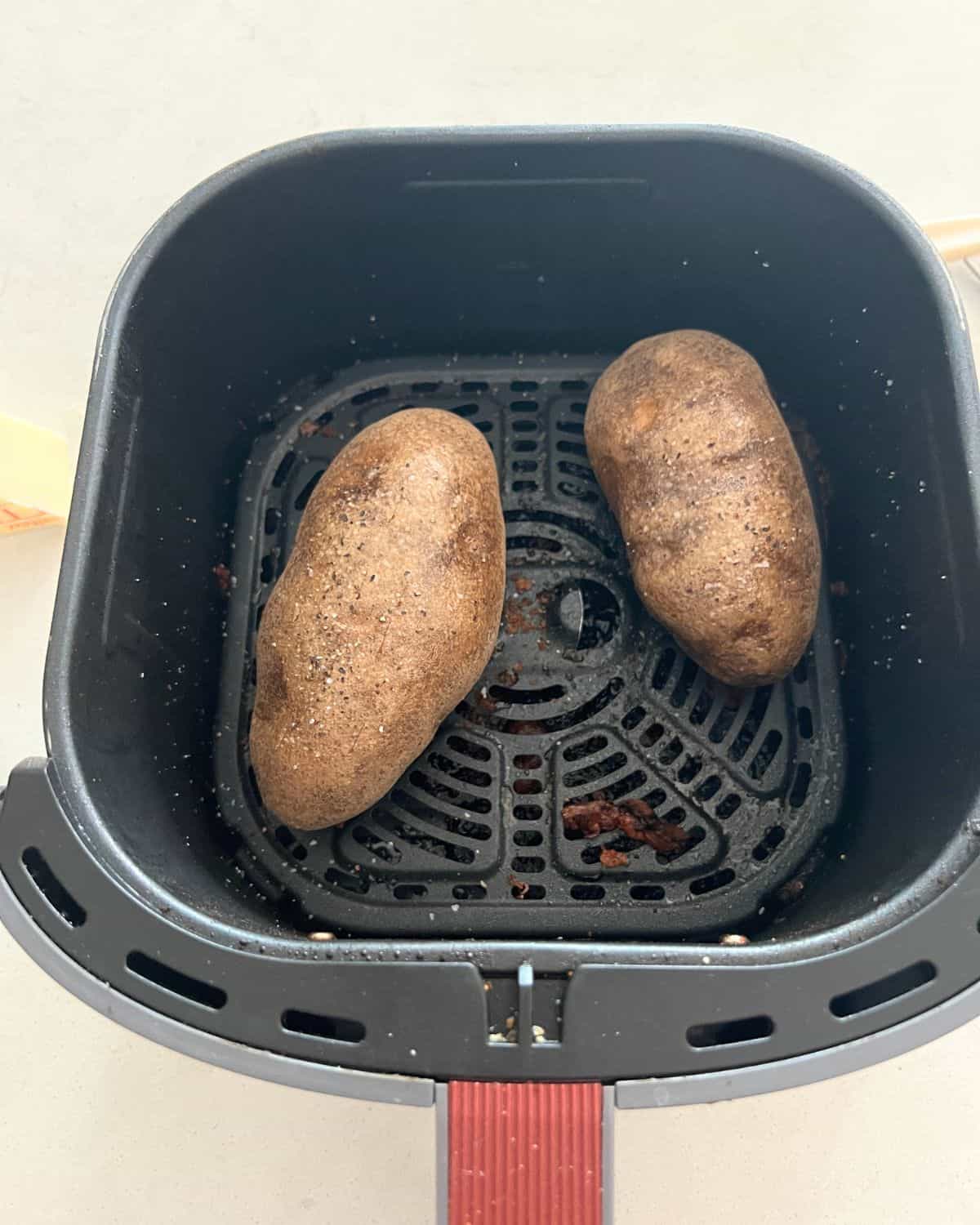 Raw uncooked potatoes in an air fryer basket. 