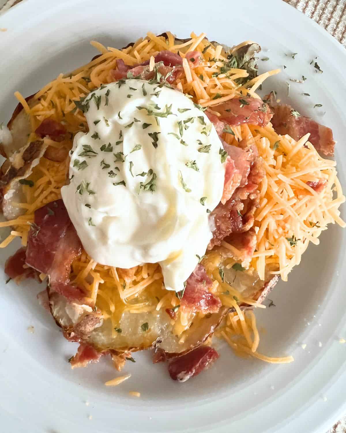 Air fryer loaded baked potato with cheese, butter, bacon, and sour cream. 