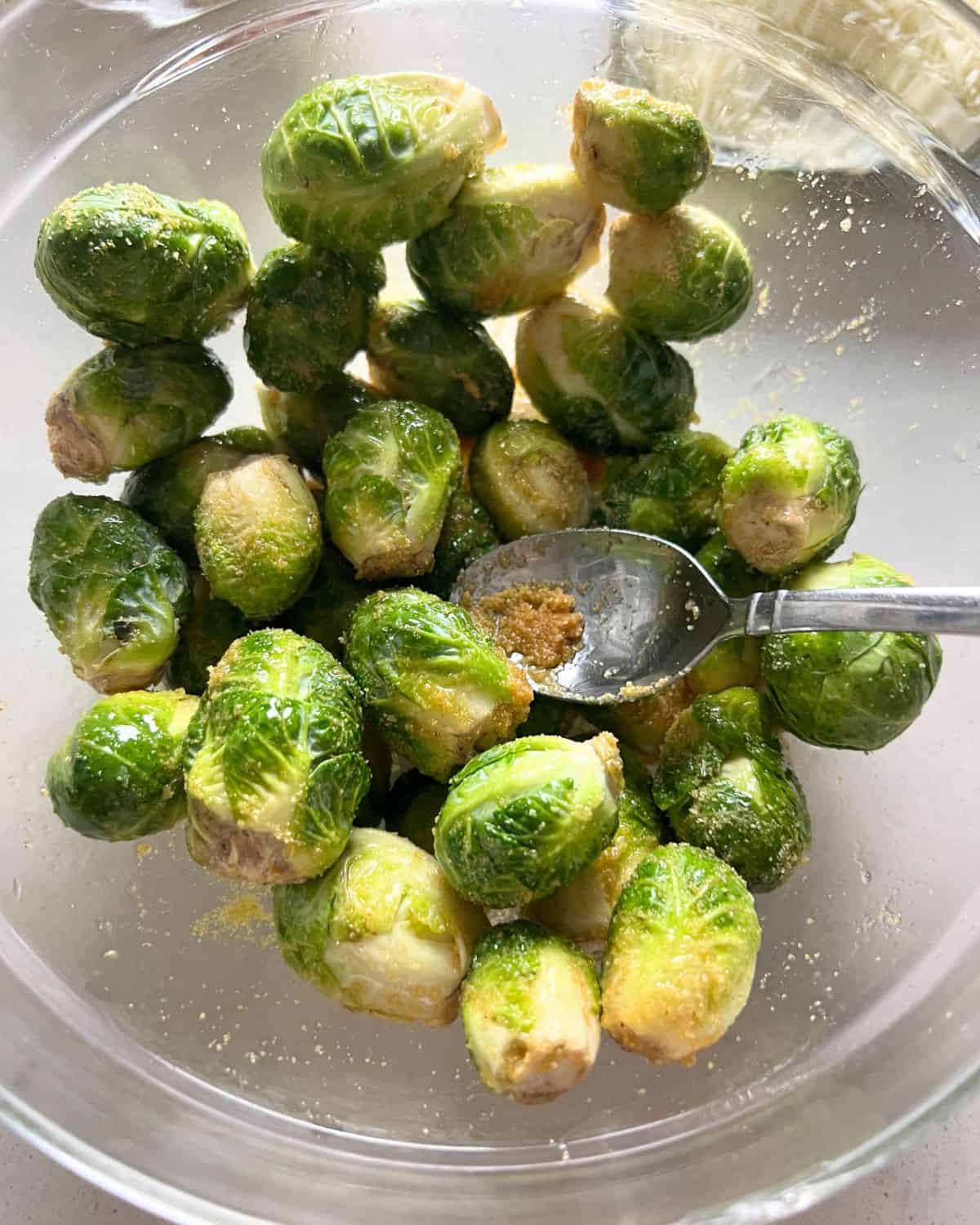 Brussel sprouts with seasonings and olive oil in a bowl. 