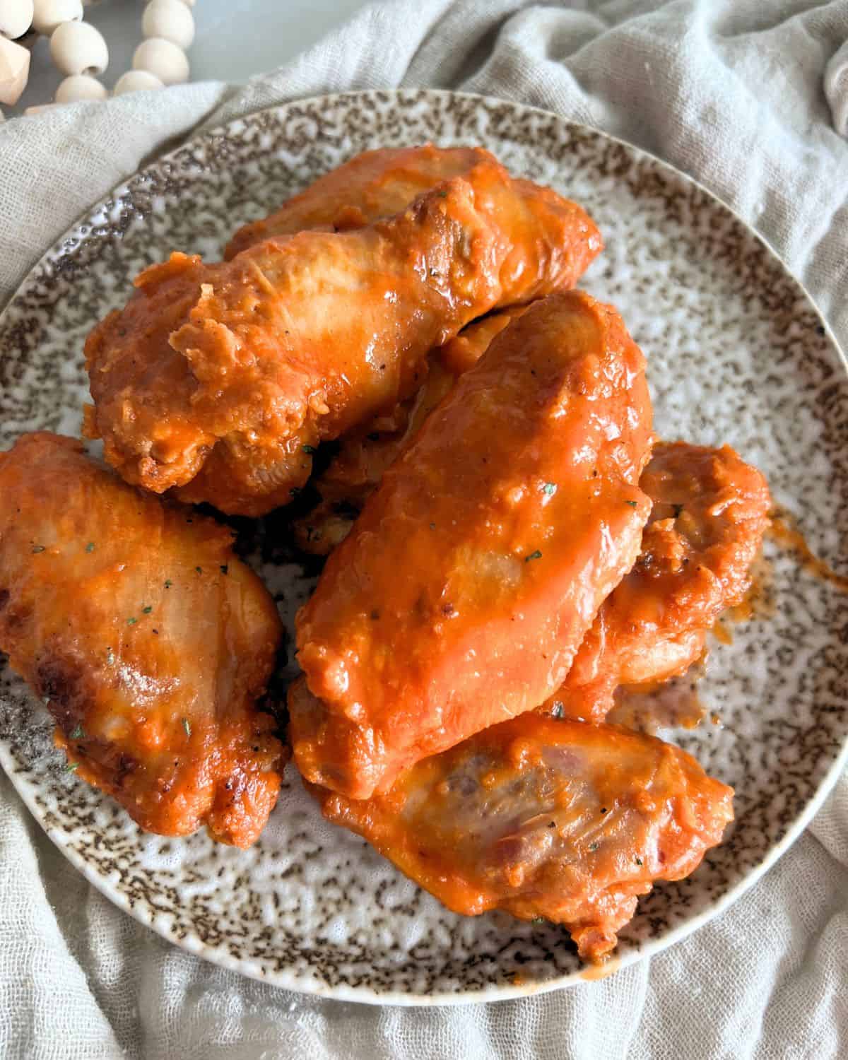 Air fryer buffalo chicken wings on a brown and white plate. 