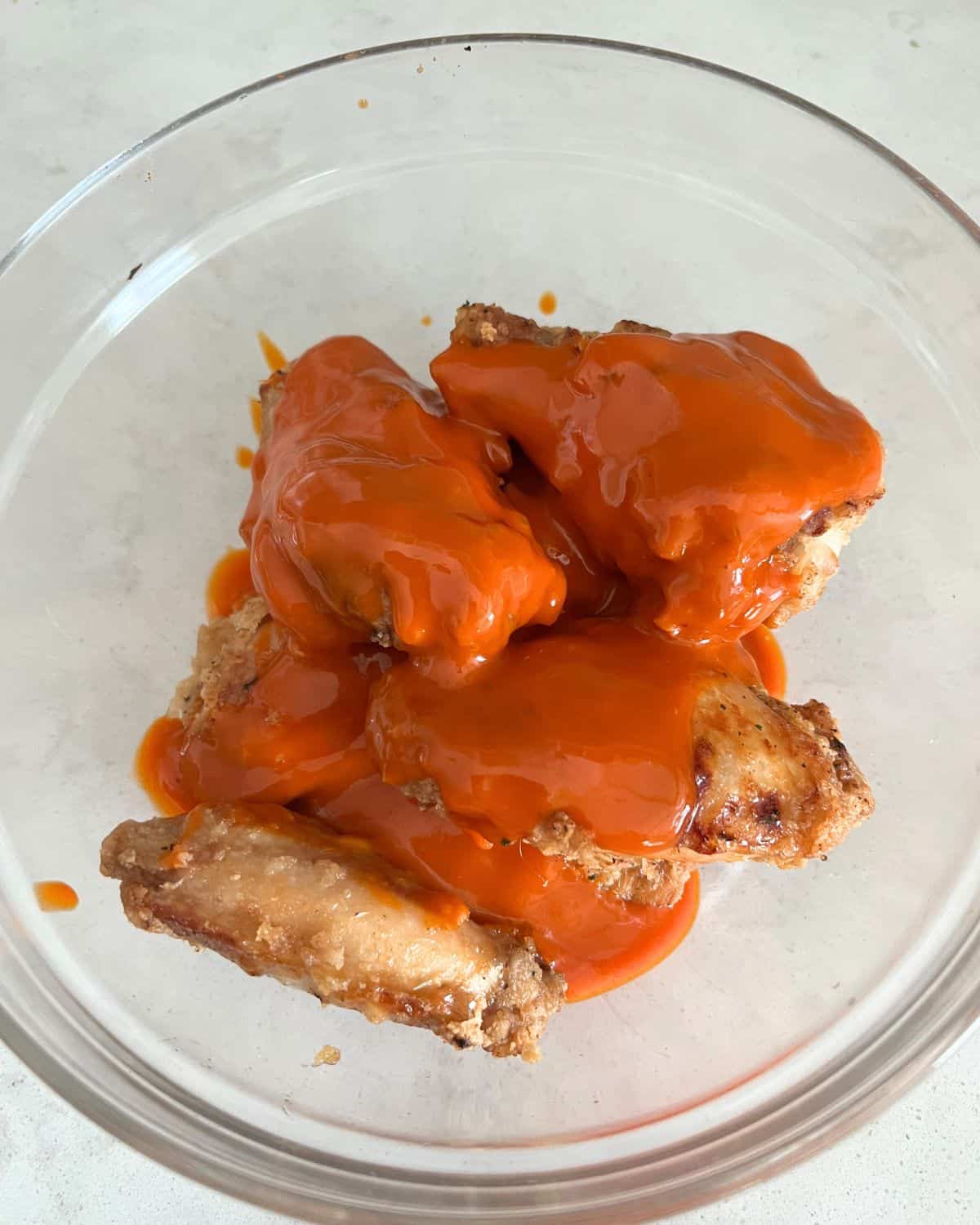 Cooked air fried chicken wings coated in buffalo sauce. 