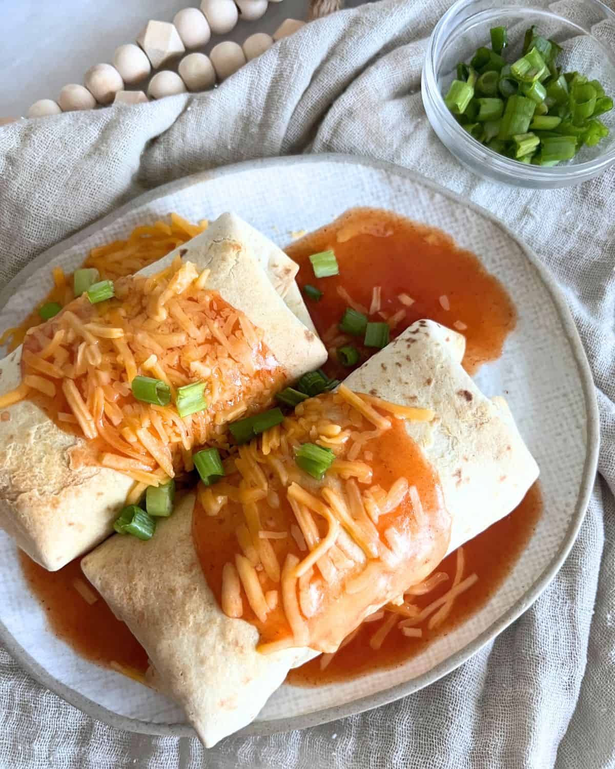 Air Fryer Chimichangas topped with enchilada sauce and cheese. 