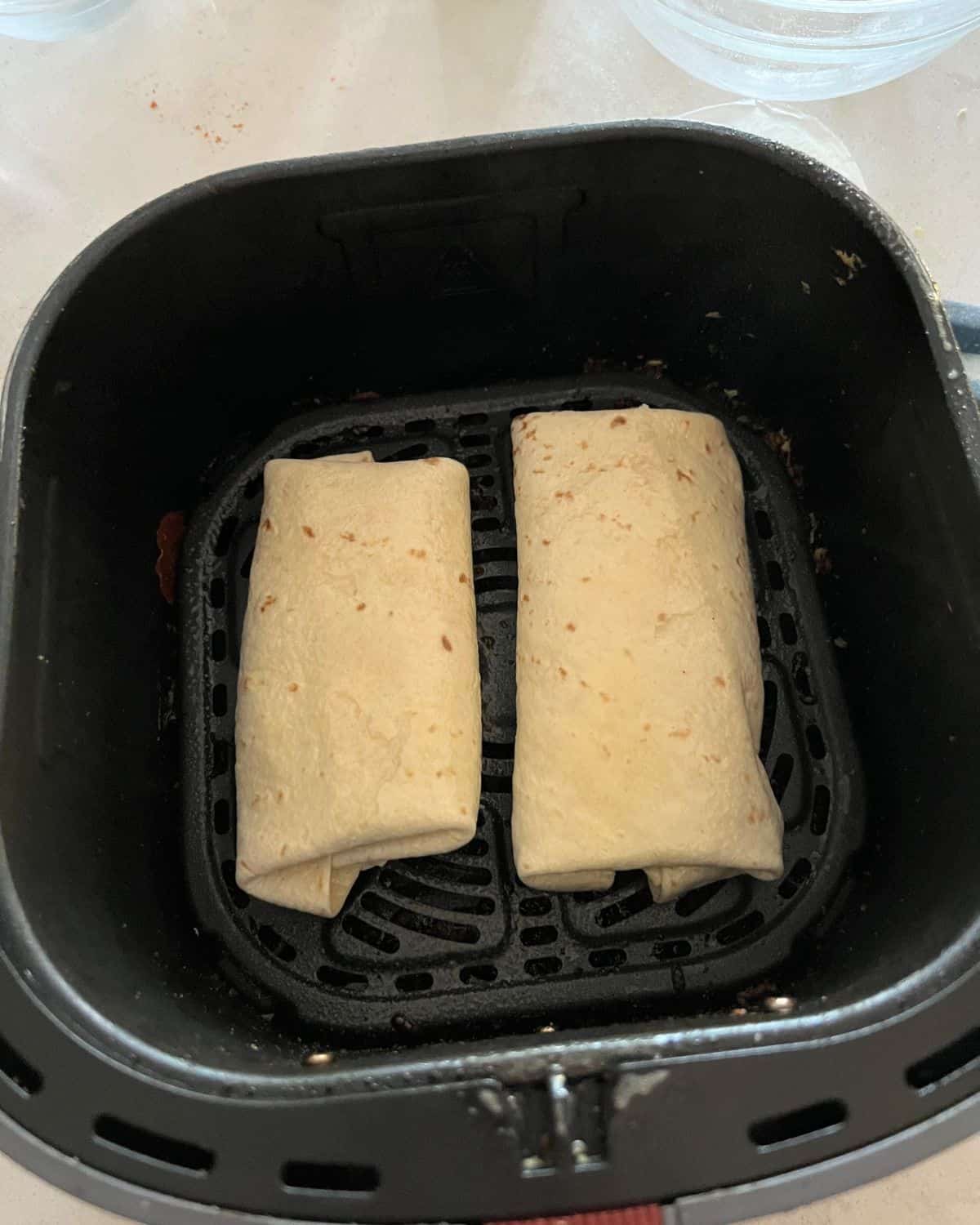 Chimichangas in air fryer basket. 